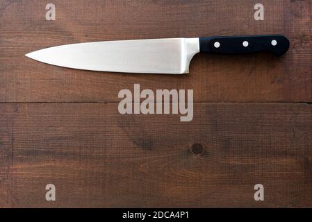 Large stainless steel carving knife, on an old wooden work table. Stock Photo