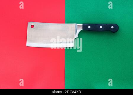 Stainless steel meat cleaver on a split red and green background. Stock Photo