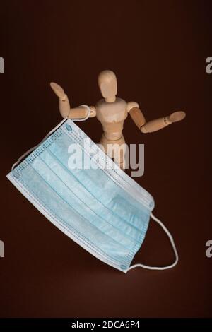 Wooden mannequin holding medical protective face mask Stock Photo