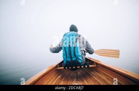 Raer view of the canoeist paddling on the foggy lake Stock Photo