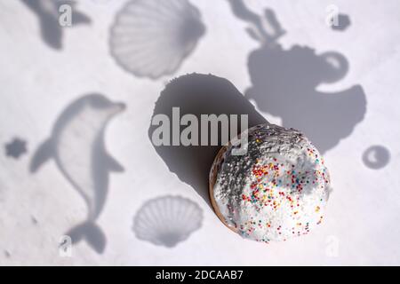 Easter cake in flat lay style with shadows of dolphin and shells on the background. Traditional food for Easter holiday in Russia. Stock Photo