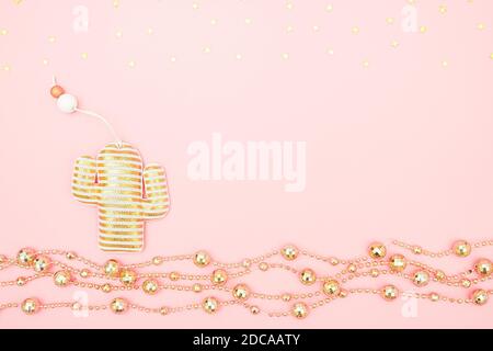 Decorative textile christmas toy cactus, golden garland and stars on pink background. Tropical Christmas or New Year night concept. Top view Creative Stock Photo