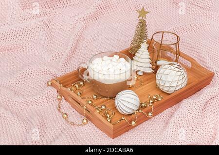 Wooden tray with cup of cocoa, marshmallows and christmas decorations on warm knitted pink plaid. Xmas or New year good morning concept. Stock Photo