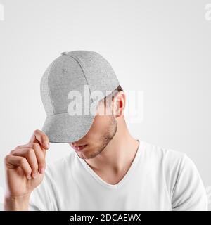Gray baseball cap template heather on guy's head straightening visor, headdress for sun protection, front view, isolated on background.Mockup of textu Stock Photo