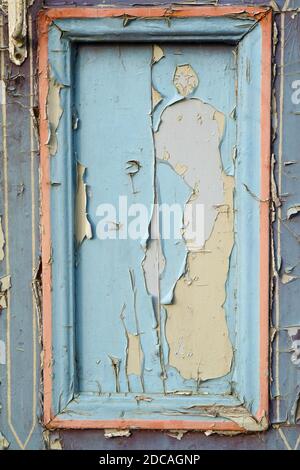 Pieces of old blue cracked paint on the vertical vintage door panel closeup Stock Photo