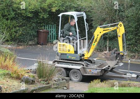 Mature man on driving a mini digger onto the back of a trailer Stock Photo