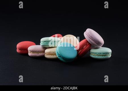 Closeup of delicious dessert cookies on table, isolated on black background. Front view of colorful sweet assorted macaroons with differest tastes. Concept of sweet pastry. Stock Photo