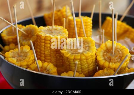 Closeup ready to eat boiled or steamed sweet corn cobs on stick in a big cooking pan, high angle view Stock Photo
