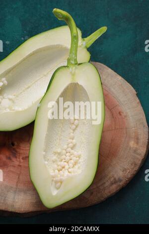 Fresh green papaya ,splitted into two pieces and arranged on a wooden piece with dark green background Stock Photo