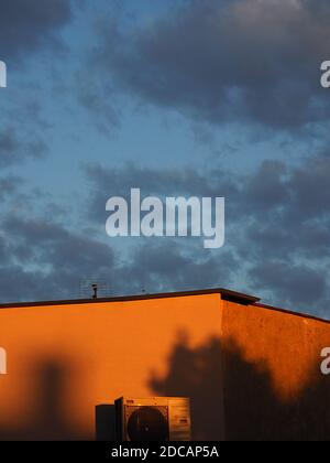 Vertical picture of a wall of a building with air conditioner on it. In late afternoon sun. Stock Photo