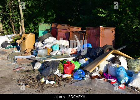 A large number of accumulated plastic bags and plastic packaging of household waste in garbage containers. The problem of garbage removal from the vil Stock Photo