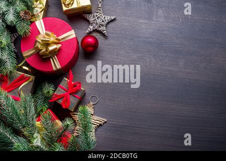 Dark wooden table with christmas decoration and gift boxes on it. Christmas or New Year holiday background. Top view. Stock Photo