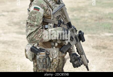 Soldier with assault rifle and flag of Bulgaria on military uniform. Collage. Stock Photo