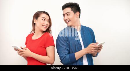 image of excited surprised loving couple isolated over white background using mobile phone. Stock Photo