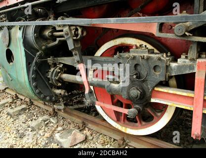 Antique locomotive driving wheels detail. Steam piston, painted wheel and connecting rods. Stock Photo