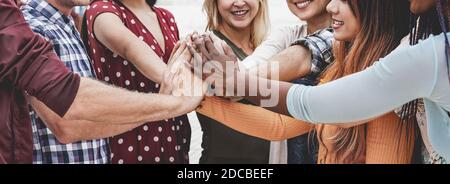 Young happy people stacking hands outdoor - Multiracial students celebrating together - Focus on black hand Stock Photo