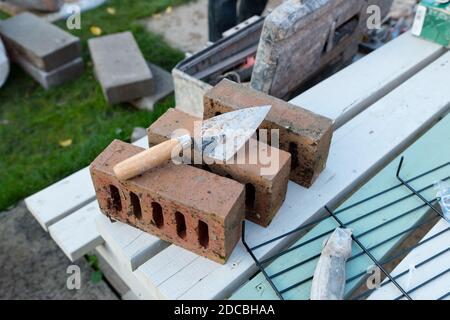 close up of bricklayer's trowel on three bricks, building a barbecue outside in autumn Stock Photo
