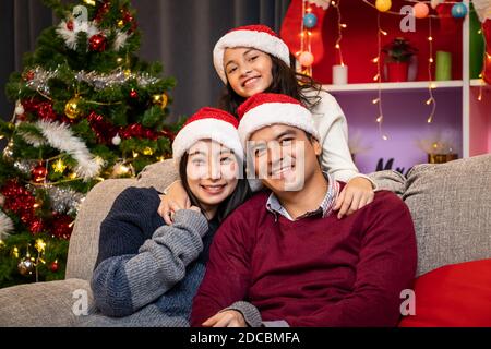 Portrait of happy family, father mother and daughter, celebrate Christmas in living room, holiday season Stock Photo
