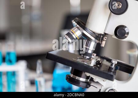Close-up of microscope examining slide of sample with test tubes in background. Concept for science and technology research in laboratory. Stock Photo