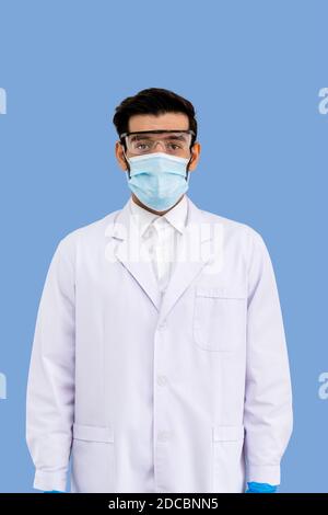 Portrait of confident male Middle Eastern Arab researcher scientist medical doctor wearing surgical mask and protection glasses standing  isolated on Stock Photo