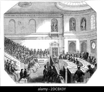 Court of Proprietors, East India Company, 1844. '...a view of the General Court Room [in Leadenhall Street, London]. Its east side is occupied by rows of seats, which rise from the floor, near the middle of the room, towards the ceiling, backed by a gallery, where the public are admitted; on the floor are the seats for the chairman, secretary, and clerks. Against the west wall, in niches, are six statues of persons who have distinguished themselves in the Company's service: Lord Clive, Warren Hastings, and the Marquis Cornwallis occupy those on the left; and Sir Eyre Coote, General Lawrance, a Stock Photo