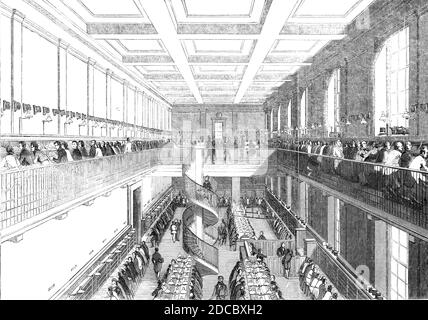 The General Post-Office; The Letter-Carriers' Office, 1844. Interior of the main post office at St Martin's Le Grand in London, view of 'a large room, with a gallery running round its four sides, and across the middle, to which are attached two spiral staircases...On the floor are two ranges of tables, divided into two double tiers of compartments; and down each side of the room is a narrow table, above which are five tiers of wooden partitions, or pigeon holes; and the gallery has also a double tier running round it; beneath the tables are enclosed cupboards for the use of the men. In the mor Stock Photo