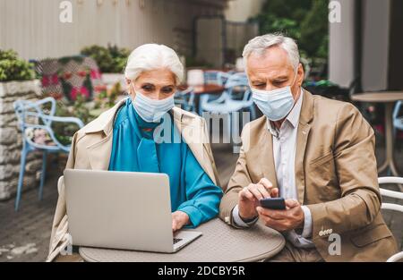 Beautiful senior couple with laptop computer sitting in a bar restaurant, communicating with family on a video call - concepts about elderly, lifestyl Stock Photo