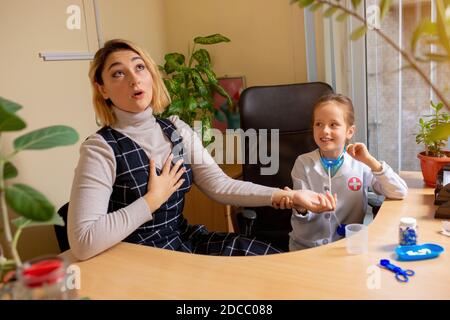 Little girl playing pretends like paediatrician doctor examining a patient in comfortabe medical office. Healthcare, childhood, medicine, education concept. Having fun while pulse measuring Stock Photo