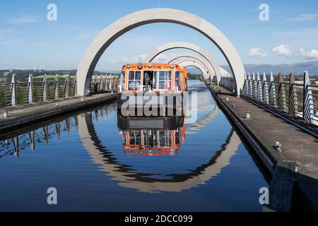 Canal boat on elevated section of canal leaving the top of the Falkirk Wheel rotating boat lift in Falkirk, Scotland, UK Stock Photo