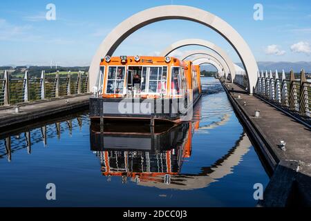 Canal boat on elevated section of canal leaving the top of the Falkirk Wheel rotating boat lift in Falkirk, Scotland, UK Stock Photo