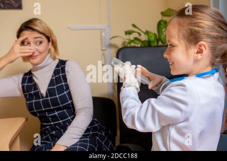 Little girl playing pretends like paediatrician doctor examining a patient in comfortabe medical office. Healthcare, childhood, medicine, education concept. Having fun while giving drugs Stock Photo