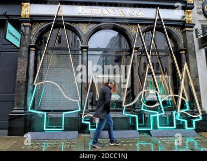 London, UK. 19th Nov, 2020. A man walks past an American luxury jewelry and specialty retailer, Tiffany & Co. seen installed with neon lights in the shape of Christmas Trees outside their Old Bond Street store.Despite the National Covid-19 Lockdown which has closed all non-essential shops till at least December 2nd, the famous luxury jewellers, Tiffany & Co have installed a neon light display in the shape of Christmas Trees outside their Old Bond Street store. Credit: SOPA Images Limited/Alamy Live News Stock Photo
