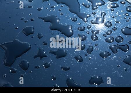 Rain drops on a blue surface. Water drops on blue metal texture. Shallow focus. Detail of red wet surface after rain Stock Photo