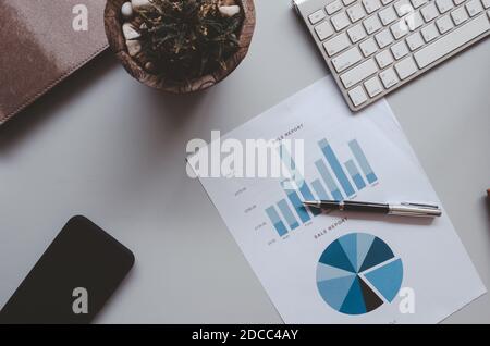 Business document Financial accounting graphs and charts analysis with keyboard and smartphone on desk.Tone vintage - top view. Stock Photo