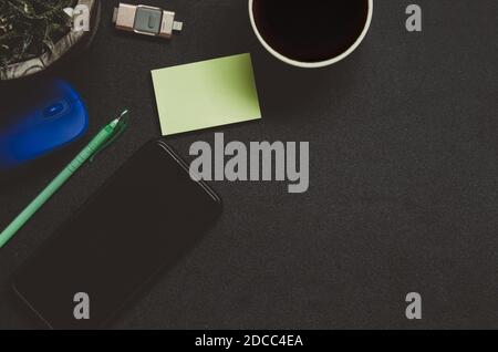 Modern dark office desk table with smart phone , coffee , tree , pen and mouse on top view and copy space.Flat lay Business concept desk black table s Stock Photo