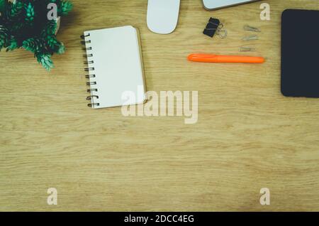 wood office desk table with smart phone , mouse , tree and supplies. Top view with copy space, flat lay. Stock Photo