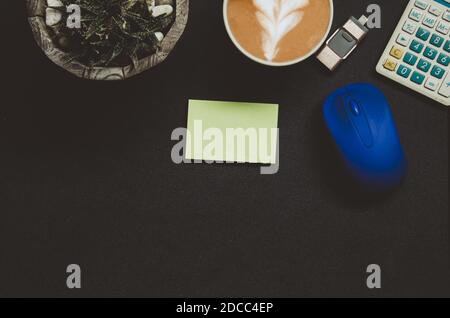 Modern dark office desk table with Office supplies Notepad , Calculator , coffee , tree , pen and mouse on top view and copy space.Flat lay Business c Stock Photo