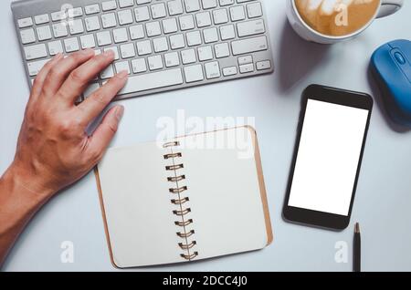 Mobile phone mockup man hand using computer keyboard Note book, coffee mug and mouse Stock Photo