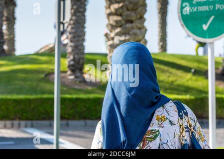 An  Arabian woman wearing traditional arabian clothes walking at the street in Dubai near Palm tree island, United Arab Emirates. Stock Photo