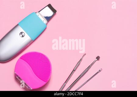 Facial cleansing tools on a pink background. Ultrasonic apparatus, silicone brush and uno spoons Stock Photo