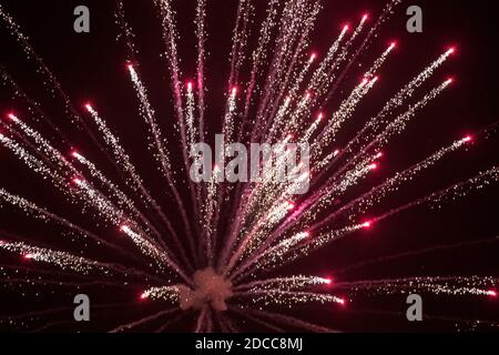 Burst of red and silver light as a pyrotechnic display firework explodes against the dark night sky in West Yorkshire U.K. Stock Photo