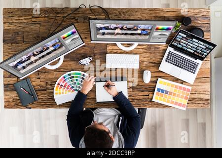 Designer Editing Photos On Multiple Computer Screens Stock Photo