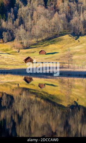 Beautiful wooden huts surrounded by autumn trees reflected in mountain lake Stock Photo