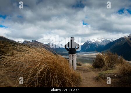 A man looking at snow-capped mountains on Bealey Spur Track in Arthur’s Pass National Park, New Zealand Stock Photo