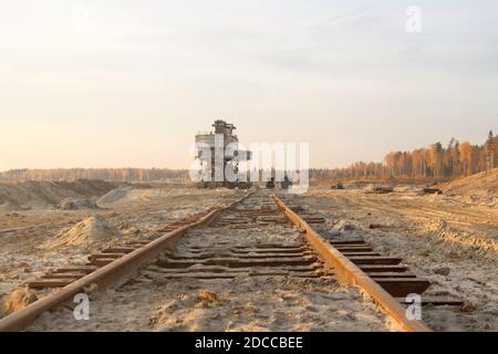 Old abandoned railway track. Rusty railroad tie. Giant stacker. Bucket chain excavator in a sand quarry. Bulk material handling Stock Photo