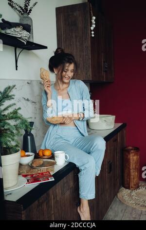 Cheerful brunette woman holding pastries in the kitchen Stock Photo