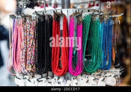 Bright, colorful jewelry made of stones, beads and metal hang on the market. Beads with beautiful stones and amulets are hung for sale at the flea Stock Photo