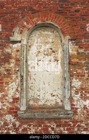 Old arched window on a red brick wall of christian church Stock Photo
