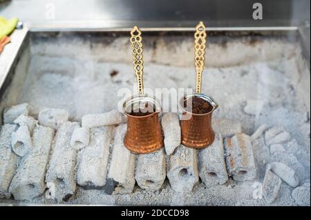 A turkish coffee pot on some wood burning with coffee inside. Street coffee in Istanbul, Turkey. Stock Photo