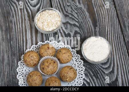 Dried fruit and oatmeal sweets. Nearby ingredients for their preparation. On black pine boards. Stock Photo